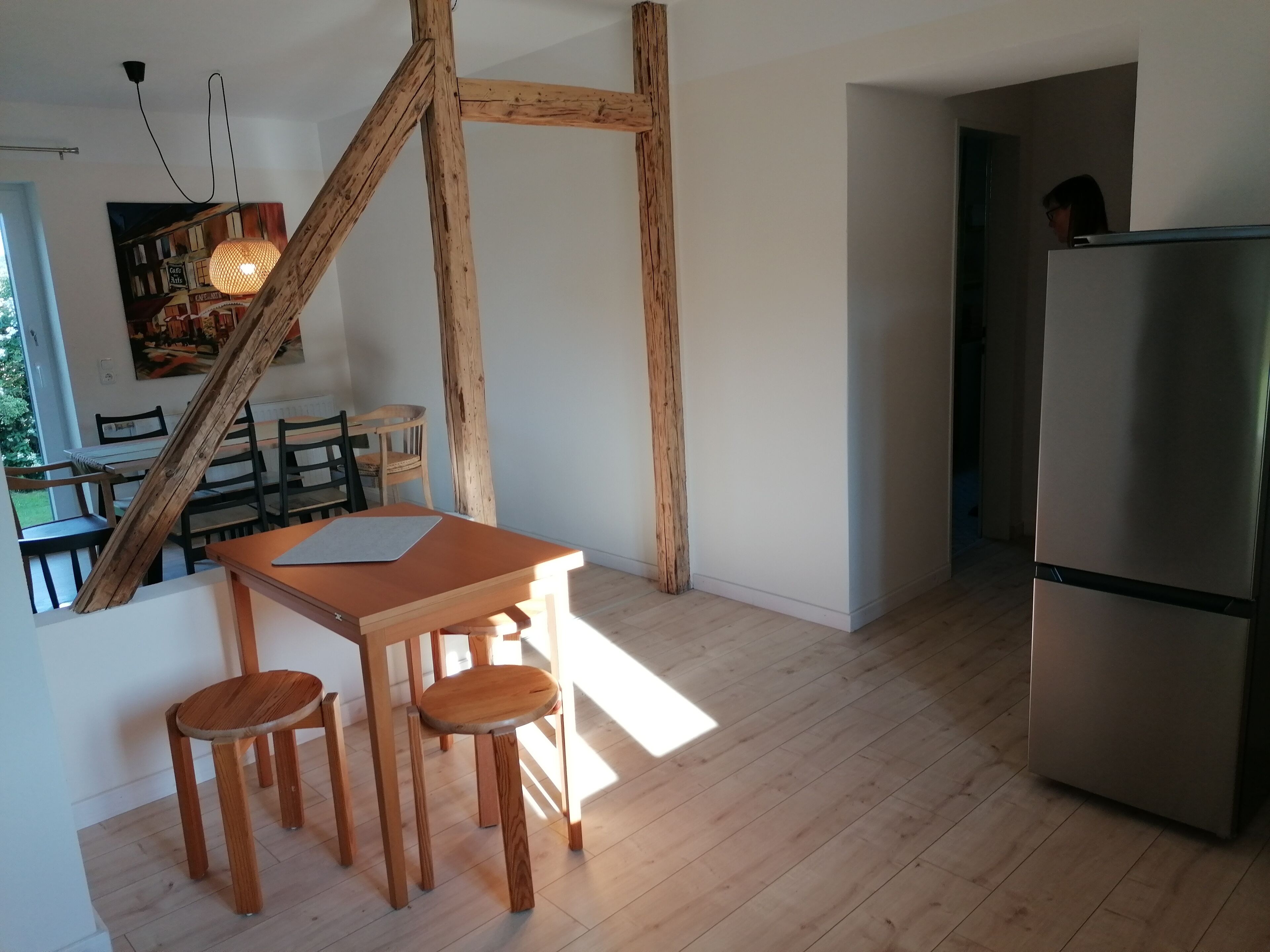 Eine moderne Küche mit Holzbalken, einem Essbereich mit Tisch und Stühlen sowie einem Kühlschrank.