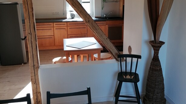 Una cocina moderna con armarios de madera, un comedor con mesa y sillas, y un gran jarrón decorativo.
