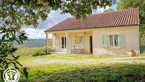 A two-story house with a tiled roof, a covered porch, and a view of the countryside.
