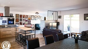 A modern kitchen with a dining area, featuring a wooden table, chairs, and a built-in oven. - Gîtes de France® - La Source du Quercy 2 (ALVIGNAC)