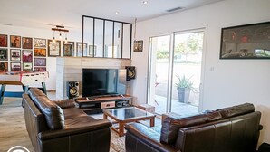A modern living room with a flat-screen TV, leather sofas, a coffee table, and a foosball table. - Gîtes de France® - La Source du Quercy 2 (ALVIGNAC)