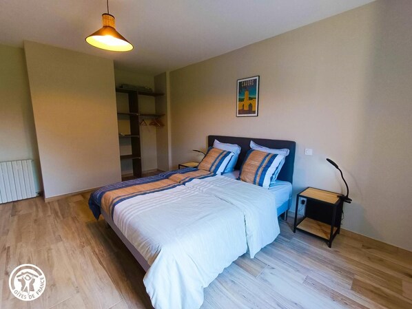 Un dormitorio con cama, mesita de noche, lámpara, radiador y armario.