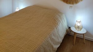 A bedroom with a bed, two wall-mounted circular woven decorations, a small table with a lamp, and a bedside table.