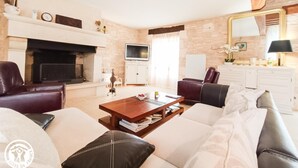 Ein modernes Wohnzimmer mit Kamin, Ledersofas, einem Couchtisch und einem Fernseher.
