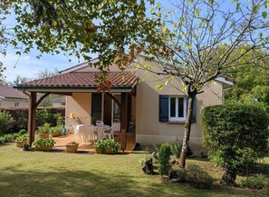 Una casa con un patio, una zona de estar al aire libre techada y un jardín con plantas en macetas.