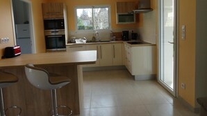 Una cucina moderna con isola centrale, elettrodomestici integrati e un'ampia finestra che fa entrare luce naturale.