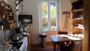 Eine kompakte Küche mit Waschmaschine, Herd, Spüle und einem Fenster mit Blick auf Grünflächen.