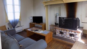 Ein Wohnzimmer mit einer Couch, Couchtisch, Fernseher, Kamin und Regalen mit Büchern und Dekoration.