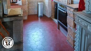 Une cuisine rustique avec des murs en pierre, une fenêtre, un évier et une cuisinière.