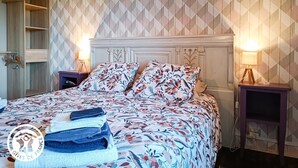Une chambre à coucher comprenant un lit, deux tables de chevet, une commode et une armoire.