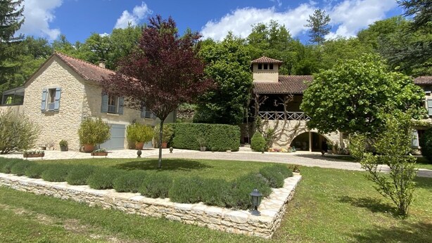 A stone house with a tiled roof, a well-maintained lawn, and a stone pathway leading to the entrance. - Gîtes de France® - Le Mazet (SAINT-MEDARD)