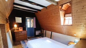 Ein gemütliches Zimmer mit Bett, Schminktisch und einem Fenster mit Vorhängen.