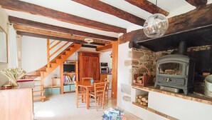 Ein gemütliches Wohnzimmer mit Kamin, Holzmöbeln und einer Treppe zu einem weiteren Raum.