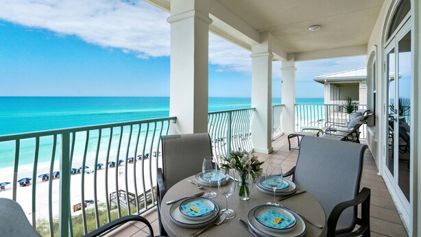 Un balcon avec vue sur l’océan, une table dressée pour le dîner et une chaise.