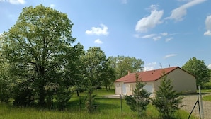 Uma casa de campo com telhado vermelho, rodeada por vegetação exuberante e árvores.