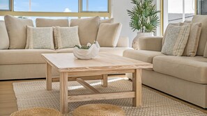 A living room with a beige sofa, a wooden coffee table, and a woven rug.