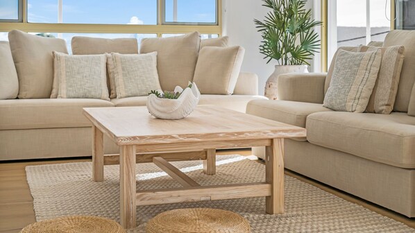 A living room with a beige sofa, a wooden coffee table, and a woven rug.