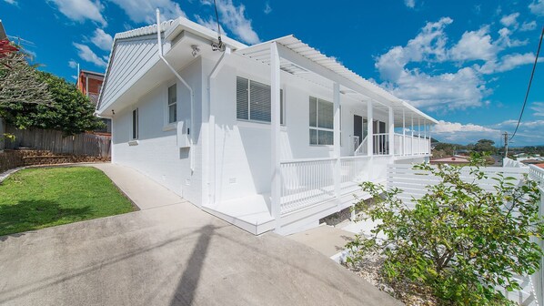 A single-story house with a covered porch, a front yard, and a clear sky.
