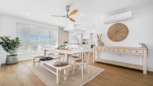 Uma cozinha moderna com armários brancos, uma mesa de jantar de madeira e um ventilador de teto.