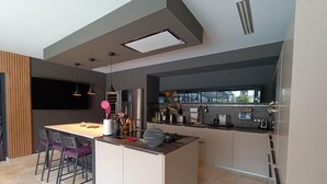 Una cocina moderna con una isla central, iluminación colgante y vistas a la ciudad.