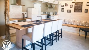 Eine moderne Küche mit Kochinsel, weißen Schränken und einem Essbereich mit Sofa und Stühlen.