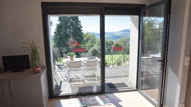 A balcony with a table and chairs, a potted plant, and a TV on a cabinet. - Gîtes de France® - 46G12361 (VIAZAC)