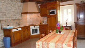 Una cocina con armarios de madera, microondas y una mesa de comedor con mantel floral.