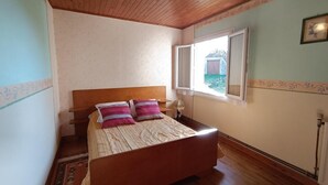 Un dormitorio con cama de madera, una ventana con vistas y un radiador.