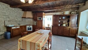 Una cocina rústica con armarios de madera, suelo de baldosas y una mesa de comedor con mantel estampado.