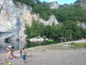 A rocky riverbank with people engaging in water activities and a green kayak.