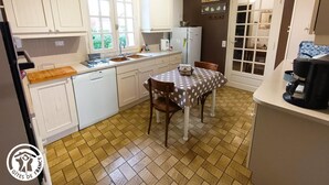 A compact kitchen with white cabinets, a dining table with a polka dot tablecloth, and a coffee machine.