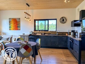Une cuisine moderne avec une grande fenêtre, une horloge et un coin repas comprenant une table et des chaises.