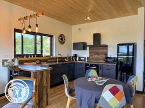 A modern kitchen with a wooden ceiling, a built-in stove, and a black refrigerator.
