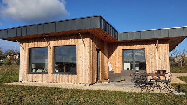 Eine moderne Holzhütte mit großen Fenstern und einer Terrassenfläche.