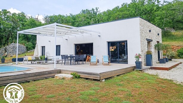 Een modern huis met een overdekte patio, buitenmeubels en een zwembad.