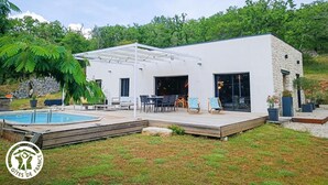 Een modern huis met een zwembad, terras en een zitgedeelte buiten.