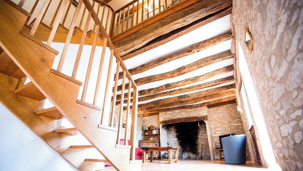 A wooden staircase leading to a stone fireplace with a tiled floor. - Gîtes de France® - Gîte de Costemagre (REILHAC)