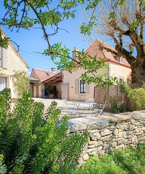 Eine Steinsichtmauer mit einer Terrassenfläche, einem Holzzaun und einem Haus mit roten Ziegeln.