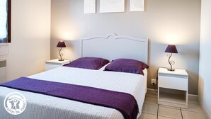 A bedroom with a bed, two bedside tables with lamps, and three wall-mounted artworks.