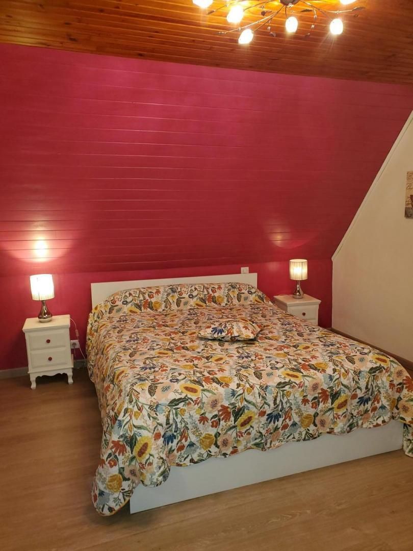 Ein Schlafzimmer mit schrägen Wänden, einer blumigen Tagesdecke, zwei Nachttischen mit Lampen und einem weißen Kopfstück.