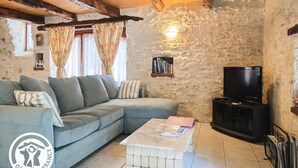 Ein gemütliches Wohnzimmer mit einem hellblauen Sofa, einem Couchtisch, einem Fernseher und einer Steinwand.