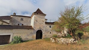 Ein Gebäude aus Stein mit einem Ziegeldach, einem Bogenportal und einem kleinen Turm.