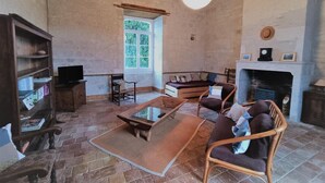 Ein gemütliches Wohnzimmer mit Steinboden, Holzmöbeln, einem Kamin und einem Bücherregal.