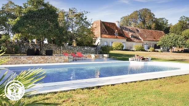 Piscina com parede de pedra e cadeiras de descanso vermelhas.