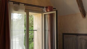 Et soveværelse med en stor seng, en skydedør til en balkon og et rustikt loft.
