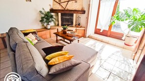 A cozy living room with a sofa, a fireplace, and a dining area. - Gîtes de France® - Le Poutoy (SAINT-SIMON)