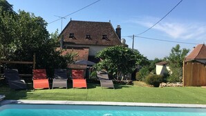 A backyard with a swimming pool, a house, and outdoor furniture. - Gîtes de France® - Gîte Le Cammas (SAINT SIMON)