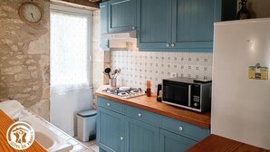 A kitchen with blue cabinets, a white stove, and a microwave. - Coumbel - Villeseque (VILLESEQUE)