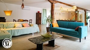 En rummelig opholdsstue med sofa, sofabord og spisebord. Der er en trappe til en etage ovenover.