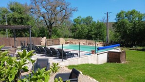 En baghave med swimmingpool, liggestole og en pergola.